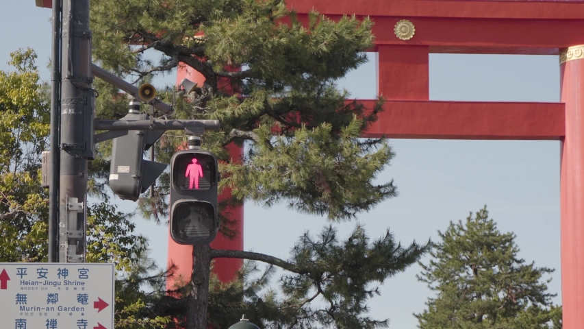 A close shot of trafic lights changing in the foreground and a red Torii in the background. Shot in Kyoto, Japan.