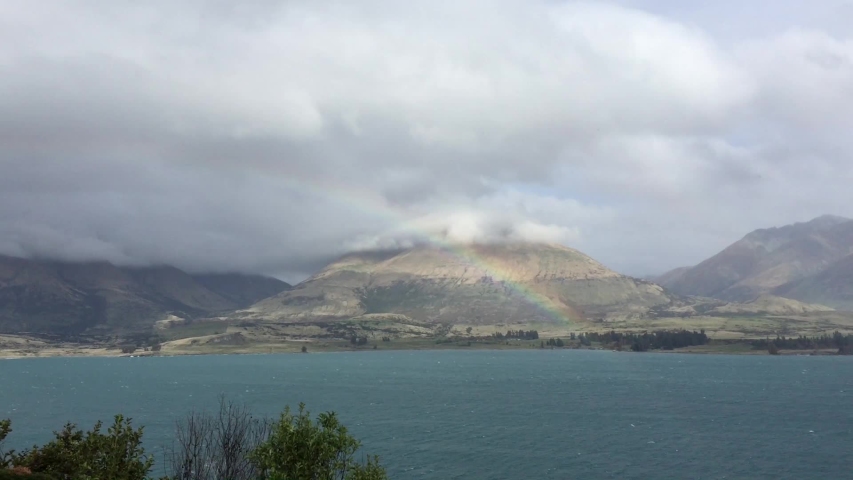 Rainbow over a lake on a cloudy day. in Queenstown, New Zealand.