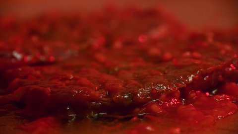 Stylistic and darkly lit macro close up of red, bloody meat being cut by a knife