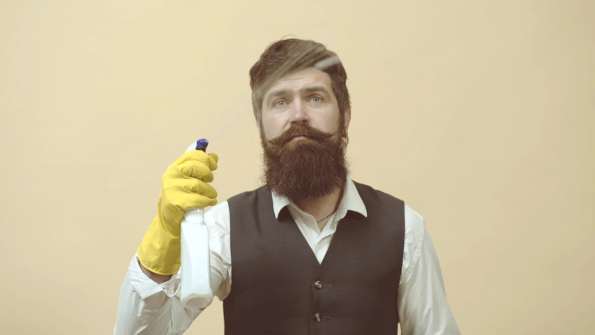 Cleaning service. Man with cleaning agents working. Portrait of man with cleaning equipment cleaning the house. Portrait of a bearded man with sponge and spray ready to clean windows