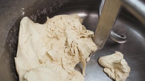 Close up for the machinery for mixing raw dough and sugar being put into the vat. Stock footage. Kneading dough at the bakery, confectionery concept.