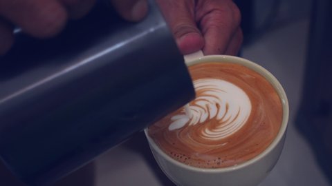 barista pouring milk to make coffee latte art.