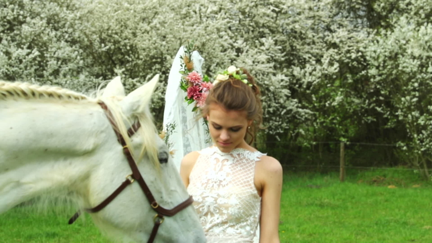 White horse in wedding day outside with bride and groom and caressing jipo head wedding teepee making background in nature.