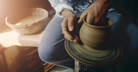 Rotation of potter's wheel, hands of ceramist make clay jug in slowmotion