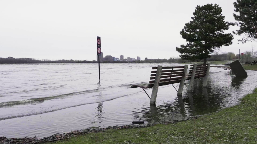 Unoccupied benches in a park surrounded by flood water from the Ottawa River