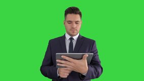 Shocked businessman watching somethng on digital tablet on a Green Screen, Chroma Key.