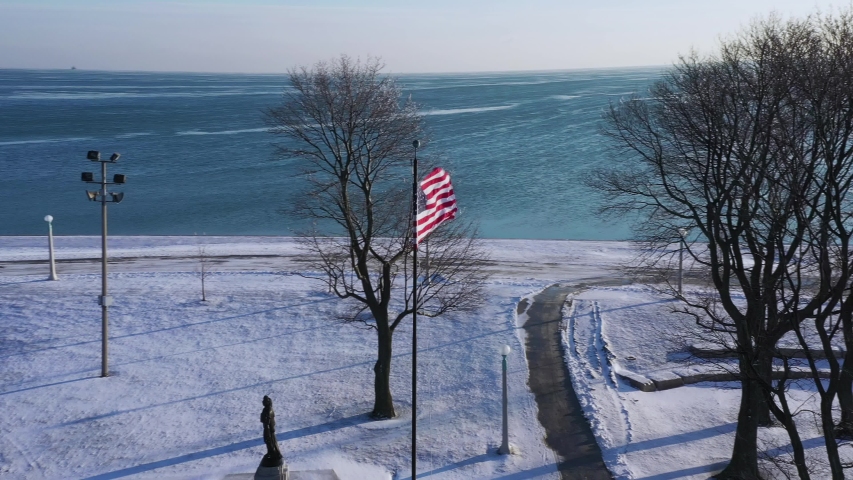American Flag Snow & Ice on Michigan Lake in Chicago Drone Shot City Flag Pole