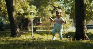 Cute baby girl exploring a park in late spring. Real life, candid 4K footage.