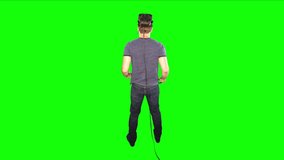 Man puts on VR headset to play game. Back of male playing virtual reality on green screen. Reverse shot behind person looking at game world. Enjoying futuristic virtual entertainment at home.