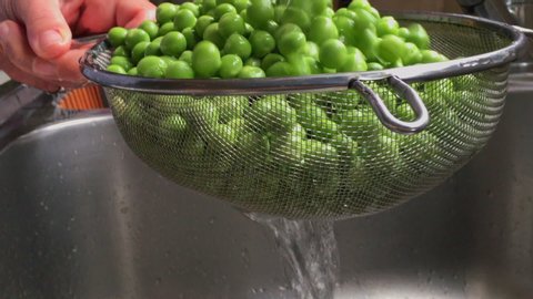 Footage Of Woman Washing And Rinsing Green Peas With Inox Colander In a Sink SLOW MOTION