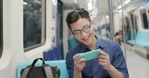 young man watch the video with phone on the MRT or train