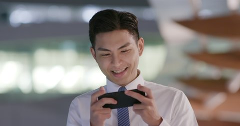 businessman play games on the phone outdoor in the evening