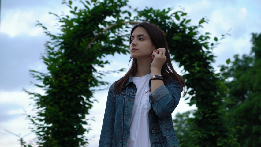cute brunette young girl in jeans jacket smiling on the street in the park in the evening
