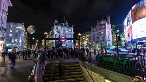 LONDON / UK - NOVEMBER 21, 2019: Timelapse view of Piccadilly Circus in London at night with full moon raising