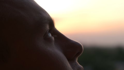 A man looks at the sky at sunset, close up
