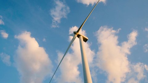 View up, bottom view of wind turbine, windmill isolated on blue sky background. Royalty high-quality free stock video footage looking up wind turbine, windmill energy converter in blue sky background