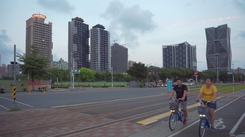 Kaohsiung, Taiwan - May 1, 2019: Awesome sunset view of Chenggong 2nd Road. Residents bicycling along the street. Evening traffic. The China Steel Corporation Headquarters and other modern buildings.