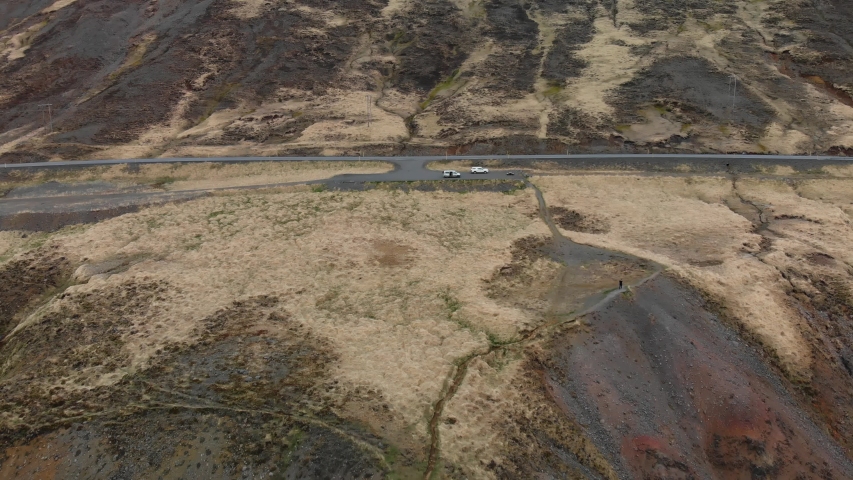Aerial footage of two parked cars up in the mountains of Iceland. Showing tourists.