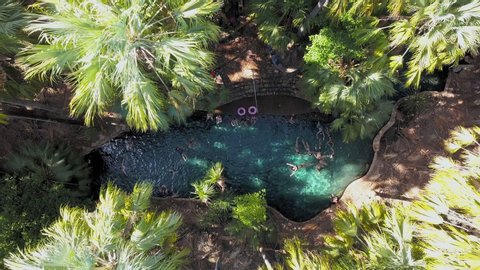 Top-down aerial rising from people swimming together in a secluded pool in Mataranka, Australia