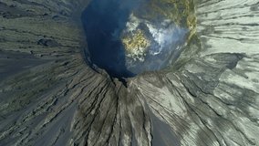 Cinematic aerial footage of Mount Bromo crater detail hole and cliff top view with smoke gas from bottom and pattern water path around step cliff