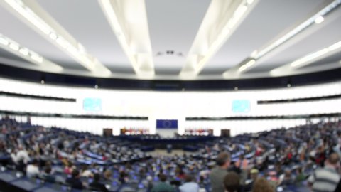Defocused blur view of European Parliament large hemicycle interior with people
