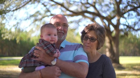 Grandparents and baby posing for picture with mother acting goofy trying to get a baby to smile