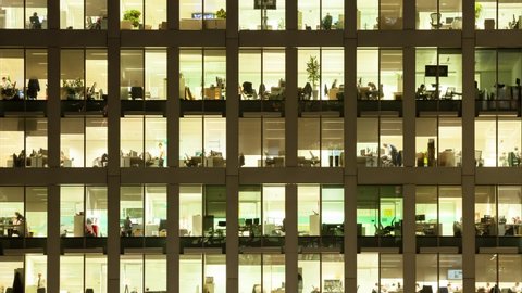 LONDON / UNITED KINGDOM  - OCTOBER 2016 : Timelapse of the exterior of an office block at night revealing the daily activity of office workers night themes of routines working late 