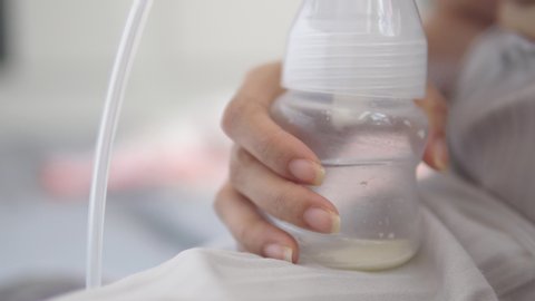 Young mother using electric breast pump pumping breast milk feeding for her baby and storing in refrigerator and provide mother's milk for future feedings.