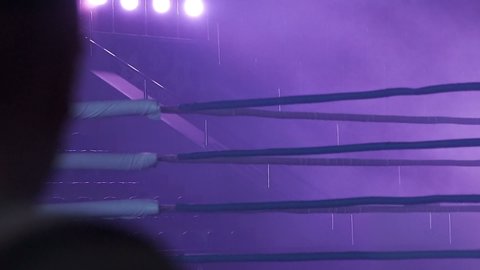 A dramatic view of the red corner of a regular boxing ring. Ropes in the corner of the ring.