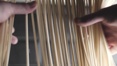 Hands take noodles. Udon noodles weigh in the kitchen of the restaurant. Noodles in a Japanese restaurant. The process of cooking udon noodles. Udon weighs evenly in the kitchen.