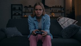 Funny looking young blonde woman playing video games. Dropping joystick on the floor, when loosing game.