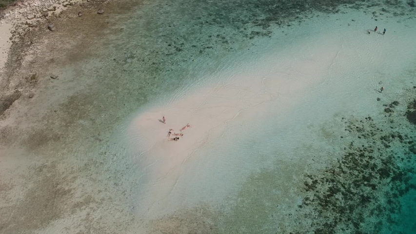 Tourists sunbathing in the shallow waters of a sandbank at a remote island in Komodo, Indonesia