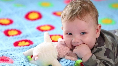 Beautiful Smiling Baby: A gorgeous little baby lies on the bed and smiles at the camera with a nice soft focus background