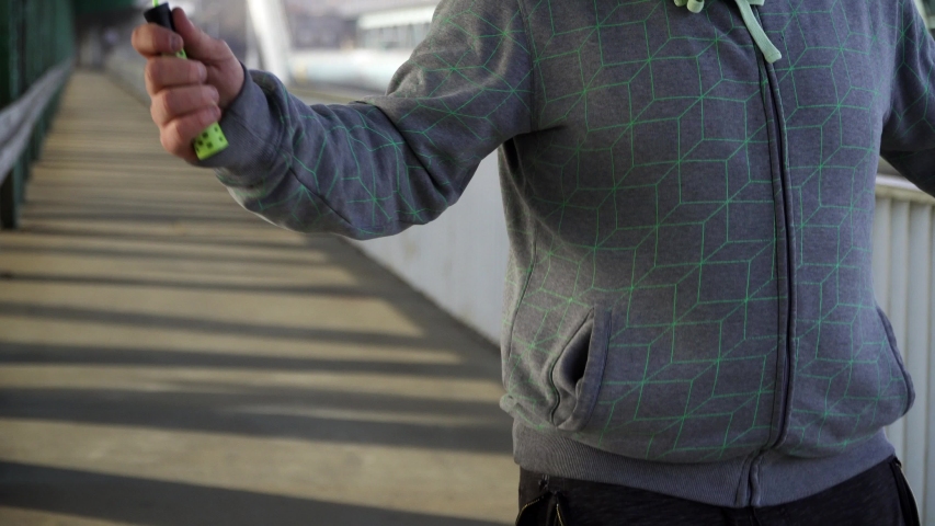Fitness freak in sportswear skipping relentlessly on a early morning on a bridge