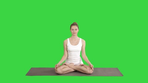 Relaxed woman in yoga position putting hands together and meditating on a Green Screen, Chroma Key.