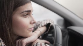 Beautiful female driver stuck in traffic jam. She leans her head and hands on a helm and looking in front of her. She is looking very sad and sorrowful.
