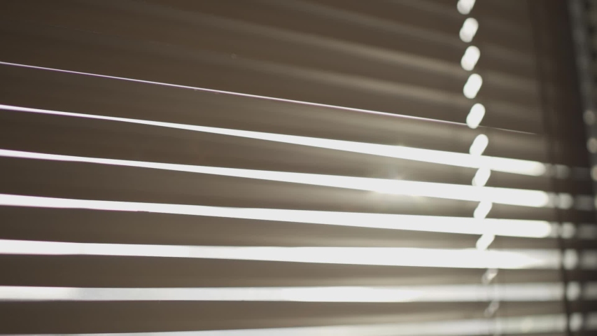 Hand pulling down window blind to peek outside - watching from an office or house room - staying inside safe in home - lonely or curious person or spy looking for mystery hiding in apartment - closeup Royalty-Free Stock Footage #1030751615