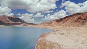 Aerial over alpine blue lake and gravel arid desert mountains in sunny day.Pamir highway silk road trip adventure in Kyrgyzstan and Tajikistan desert,central Asia.4k drone flight establisher video