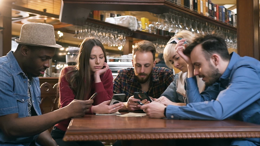 Unhappy, boring group of hipster friends using smart phone during resting in the pub, bar. Royalty-Free Stock Footage #1030762241