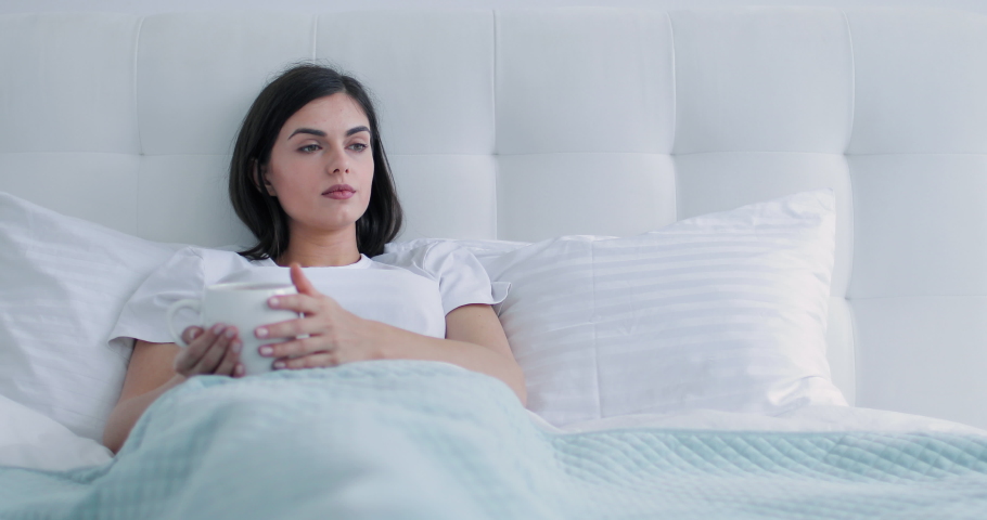 Beatiful brunette girl using futuristic hologram hud panel screen for browsing internet while lying in the bed Royalty-Free Stock Footage #1030763102