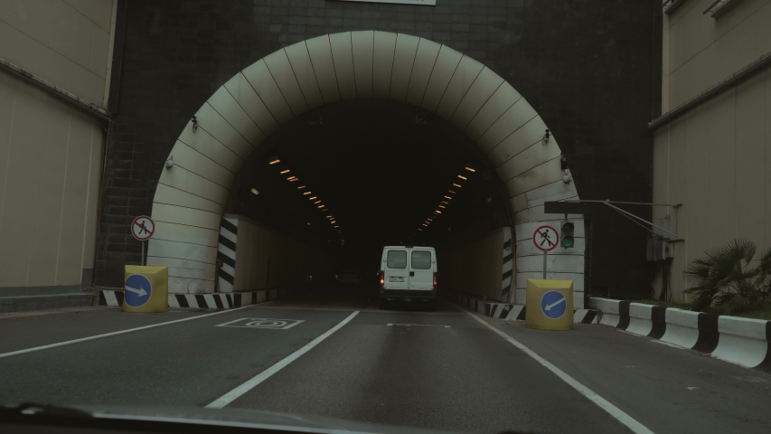 View from the car passing through the tunnel. The car passes through a long tunnel in the mountain. The car pulls into a narrow single-lane tunnel Royalty-Free Stock Footage #1030763765