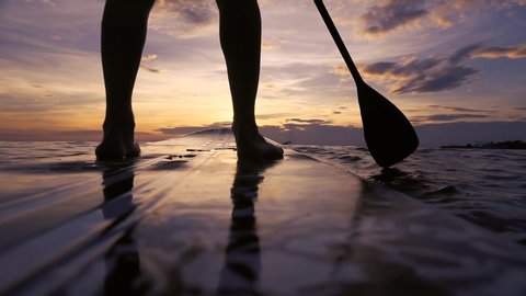 SUP paddle board on the beach, close up of standing legs and paddle