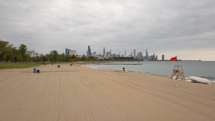 Chicago beach, Lake Michigan, and skyline shot by drone from south of the city.  The shot starts low and ascends.  It was shot in the morning with an overcast sky.  