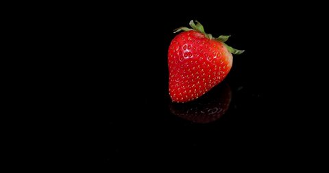 Fresh red strawberry isolated on black background with reflection. rotating 360 degrees seamless loop