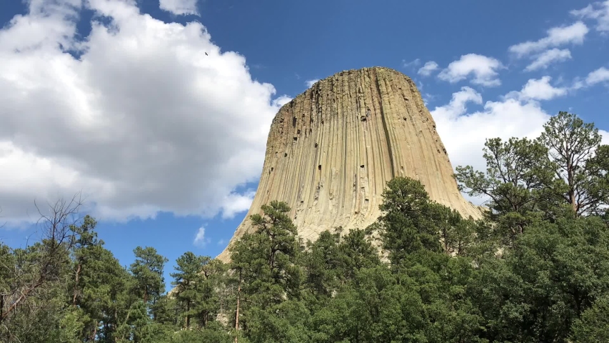 Medium close up time lapse shot of the Devil’s Tower in Wyoming, with thick white clouds moving over it