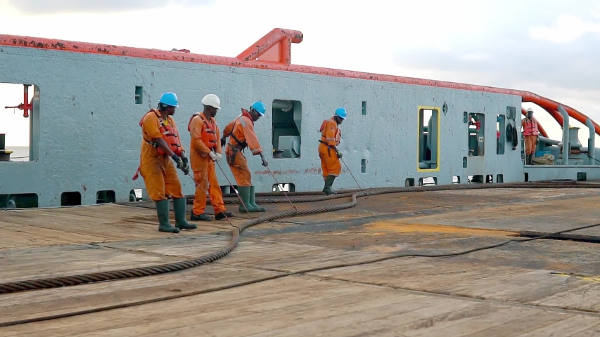 Anchor-handling Tug Supply AHTS vessel crew preparing vessel for static tow tanker lifting. Ocean tug job. AB and Bosun on deck. Good teamwork