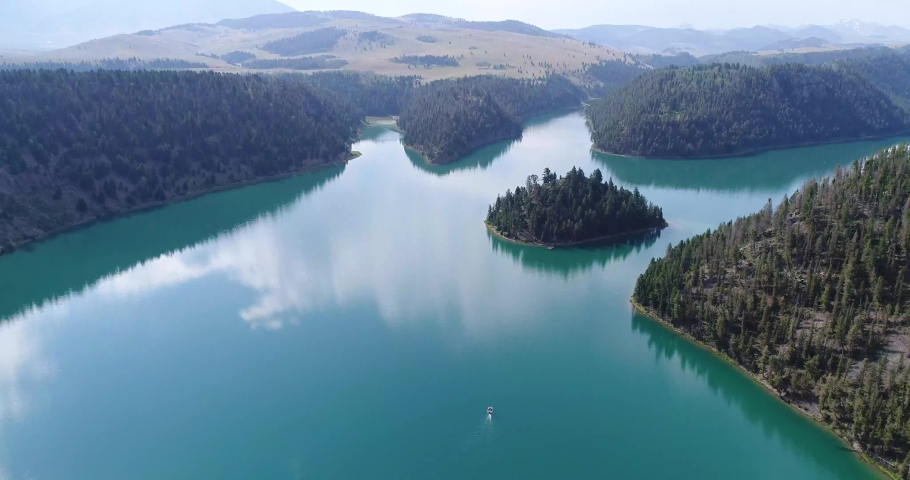 Aerial wide shot of Wade Lake with a boat in Montana during the summer. Mountains in background.