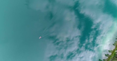 Top down aerial of boat on lake with heavy reflection of clouds during the summer.