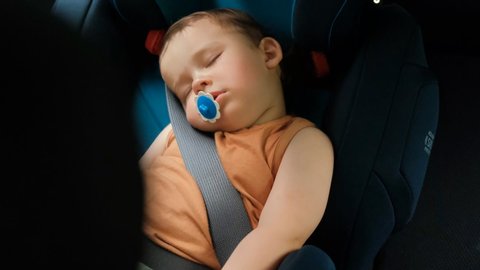 A little boy sleeps in a chair. Children's safety systems in cars.