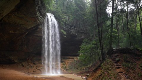 Ash Cave, an enormous recess cave in the Hocking Hills of Ohio, is graced by a plunging waterfall in this seamlessly looping footage.